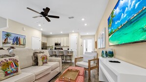 Un soggiorno moderno con un divano, un tavolino, una TV e una ventola a soffitto.