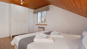 A bedroom with a bed, a wardrobe, a window, and a ceiling light.