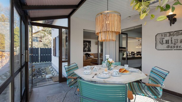 A dining area with a round table, chairs, and a hanging light fixture.