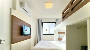A hotel room with a bed, a TV mounted on the wall, an air conditioning unit, and a window with curtains. - Comfort club with ocean view, air conditioning and nearby. Beto Carrero (Penha)