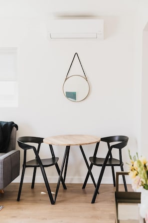 Minimalistinen ruokailutila, jossa on pyöreä puinen pöytä ja neljä ainutlaatuisella designilla varustettua mustaa tuolia.