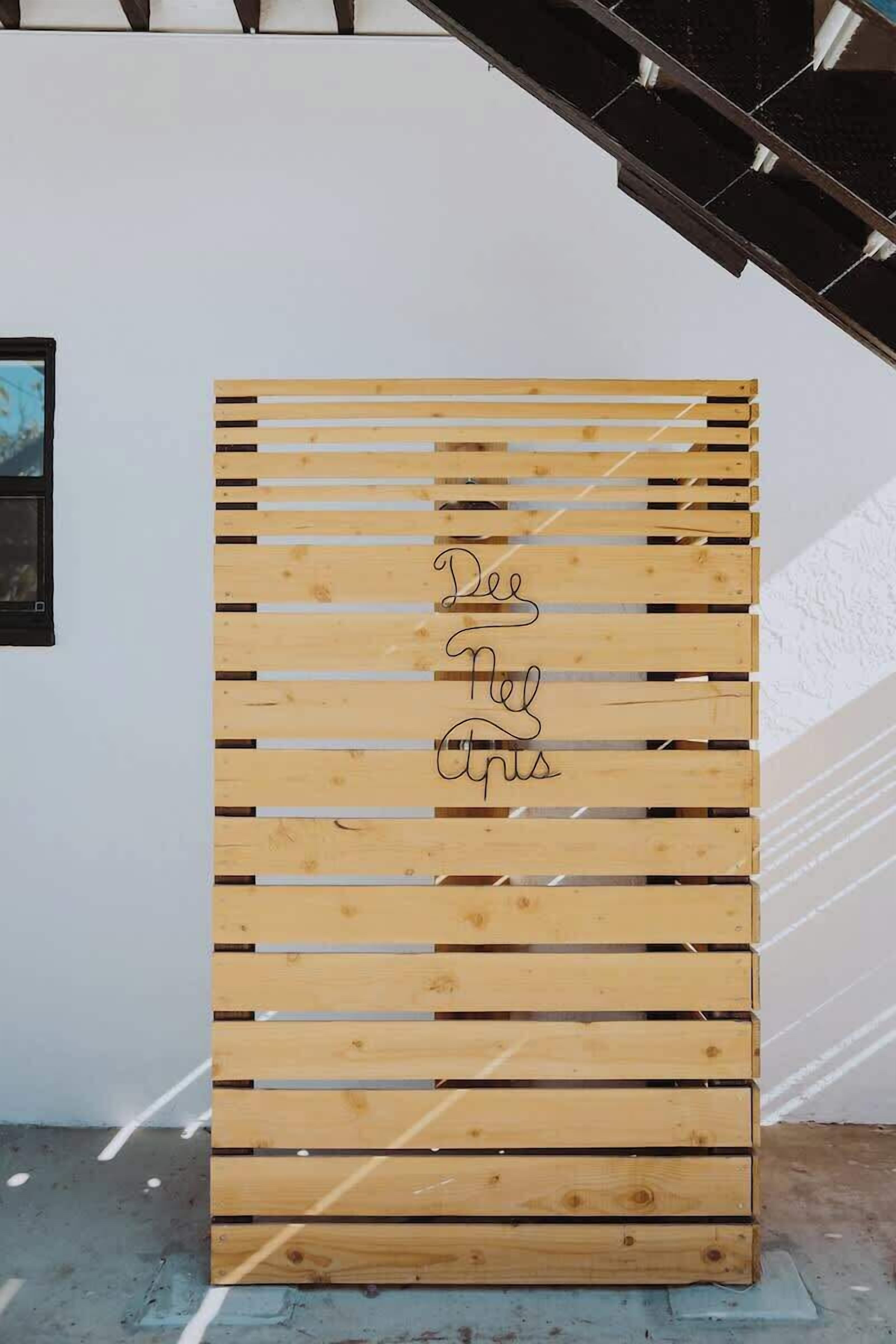 A wooden slat wall with the text "Dee Nels" written on it.