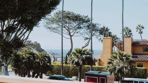 Vista costera con palmeras, una valla de madera y un edificio de techo rojo.