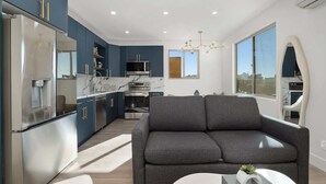 A modern kitchen with dark blue cabinets, a marble countertop, and stainless steel appliances. - Refined Retreat in Banker's Hill (San Diego)