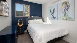 A bedroom with a bed, a dresser, a window, and abstract art on the wall. - Refined Retreat in Banker's Hill (San Diego)