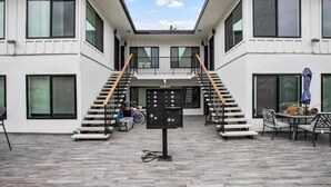 Un edificio moderno con una escalera central, un balcón y una zona de estar con una mesa y sillas.