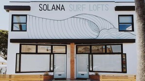 A building named 'SOLANA SURF LOFTS' with large windows and a wave design on the facade.