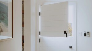 A room with a white door, a framed picture on the wall, and a table with a bowl of lemons.