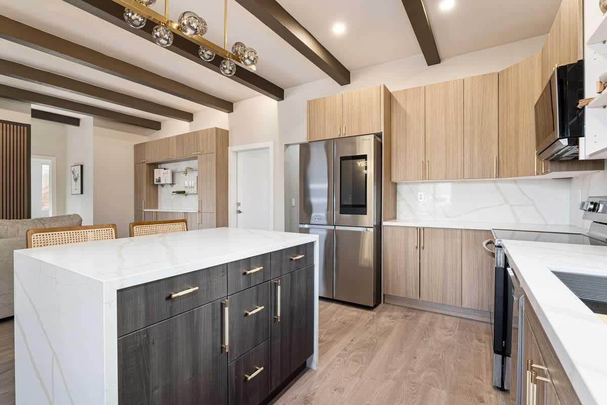 A modern kitchen with a central island, built-in appliances, and a dining area with a sofa and chairs.