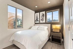 A bedroom with a bed, a bedside table with a lamp, and three framed artworks on the wall. - Luxe 3BR Dual Suite in Banker's Hill | Downtown SD (San Diego)