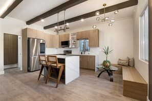 A modern kitchen with a central island, stainless steel appliances, and a seating area with a plant. - Luxe 3BR Dual Suite in Banker's Hill | Downtown SD (San Diego)