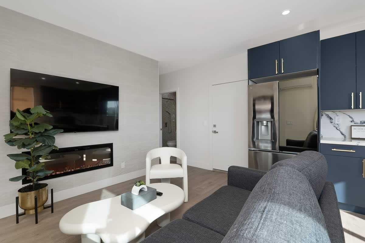 A modern living room with a flat-screen TV, a fireplace, a sofa, and a dining area.