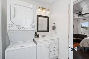 A modern bathroom with a built-in washing machine, a vanity with a mirror, and a ceiling fan. - Perfect Studio in the Best Location of North Park! (San Diego)