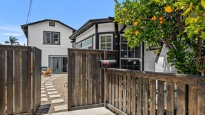 A gated driveway leading to a two-story house with a mailbox and a tree with oranges. - Perfect Studio in the Best Location of North Park! (San Diego)