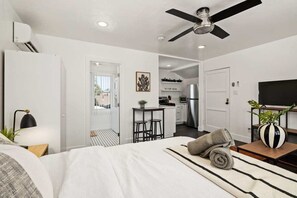 A modern hotel room with a bed, a ceiling fan, a TV, a kitchen area, and a balcony. - Perfect Studio in the Best Location of North Park! (San Diego)