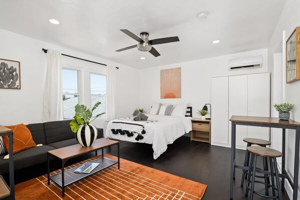 A modern bedroom with a bed, a ceiling fan, a desk, and a bar stool. - Perfect Studio in the Best Location of North Park! (San Diego)
