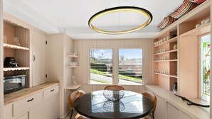 Cozinha moderna com mesa de jantar redonda, armários embutidos e vista através de grandes janelas.