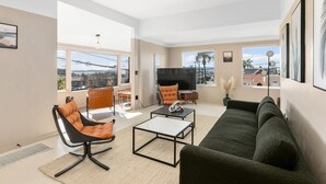 Uma sala de estar moderna com um sofá, uma poltrona, uma mesa de centro e uma televisão.