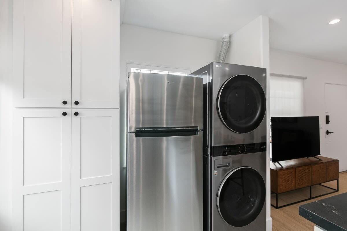 Una cocina moderna con un refrigerador de acero inoxidable, un horno empotrado y una puerta de horno negra.