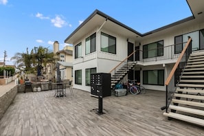 Ett modernt hus i två våningar med en träveranda, en trappa och en cykel.