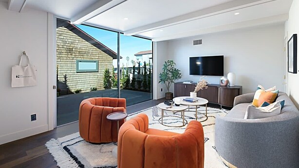 Un salon moderne comprenant un canapé, des fauteuils, une table basse et un téléviseur.