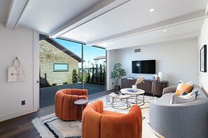 Uma sala de estar moderna com um sofá, poltronas, uma mesa de centro e uma televisão.