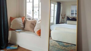 Une chambre avec une grande fenêtre, un lit, un canapé et un miroir.