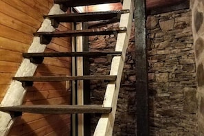 A wooden staircase with a stone wall on one side.