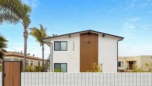 Ein modernes, zweistöckiges Gebäude mit weißer Fassade, einer Holzpaneel-Akzentwand und einer gut sichtbaren Adresse.
