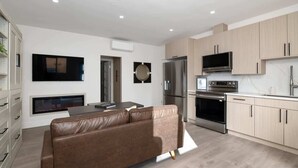 A modern kitchen with built-in appliances, a flat-screen TV, and a dining area with a leather sofa. - Chic Studio in Banker's Hill, Steps to Balboa Park (San Diego)