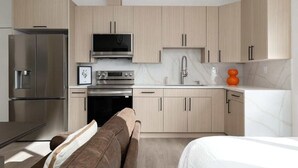 A modern kitchen with light wood cabinets, stainless steel appliances, and a built-in oven. - Chic Studio in Banker's Hill, Steps to Balboa Park (San Diego)