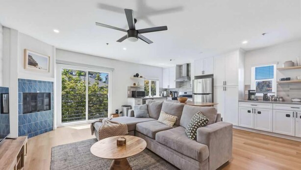 A modern living room with a grey sofa, a round coffee table, and a ceiling fan. - Fletcher Cove Solana Beach 2BD Coastal Apartment (Solana Beach)