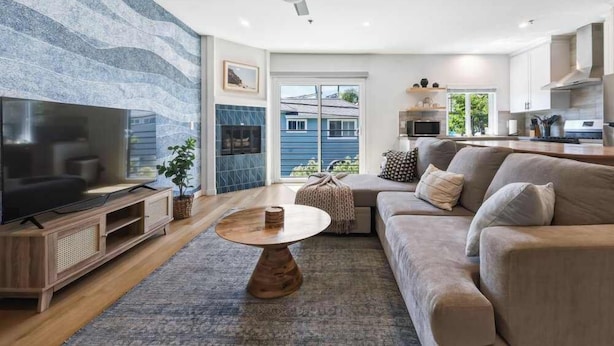 A modern living room with a flat-screen TV, a ceiling fan, a sofa, and a coffee table.