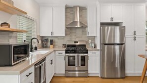 A modern kitchen with white cabinets, stainless steel appliances, a built-in oven, and a microwave. - Stylish 2BD Peek-a-boo Ocean View High-End Stay (Solana Beach)