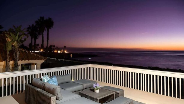 A balcony with a grey sectional sofa, a small table, and wicker chairs. - 4BR Home Sunset Cliffs Oceanfront - Cliffside View (San Diego)