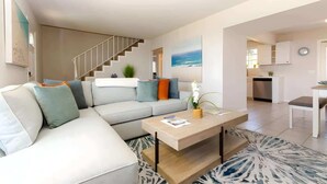 A modern living room with a sofa, coffee table, and a staircase leading to an upper floor. - 4BR Home Sunset Cliffs Oceanfront - Cliffside View (San Diego)