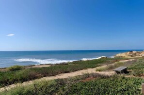 A coastal landscape with a sandy beach, sparse vegetation, and a clear blue sky. - 4BR Home Sunset Cliffs Oceanfront - Cliffside View (San Diego)