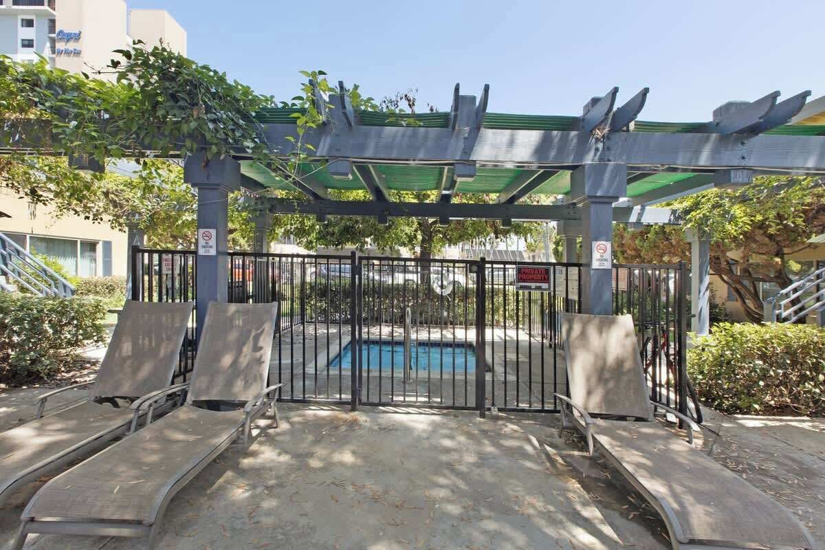 A gated pool area with a metal gate, a pool, and lounge chairs.