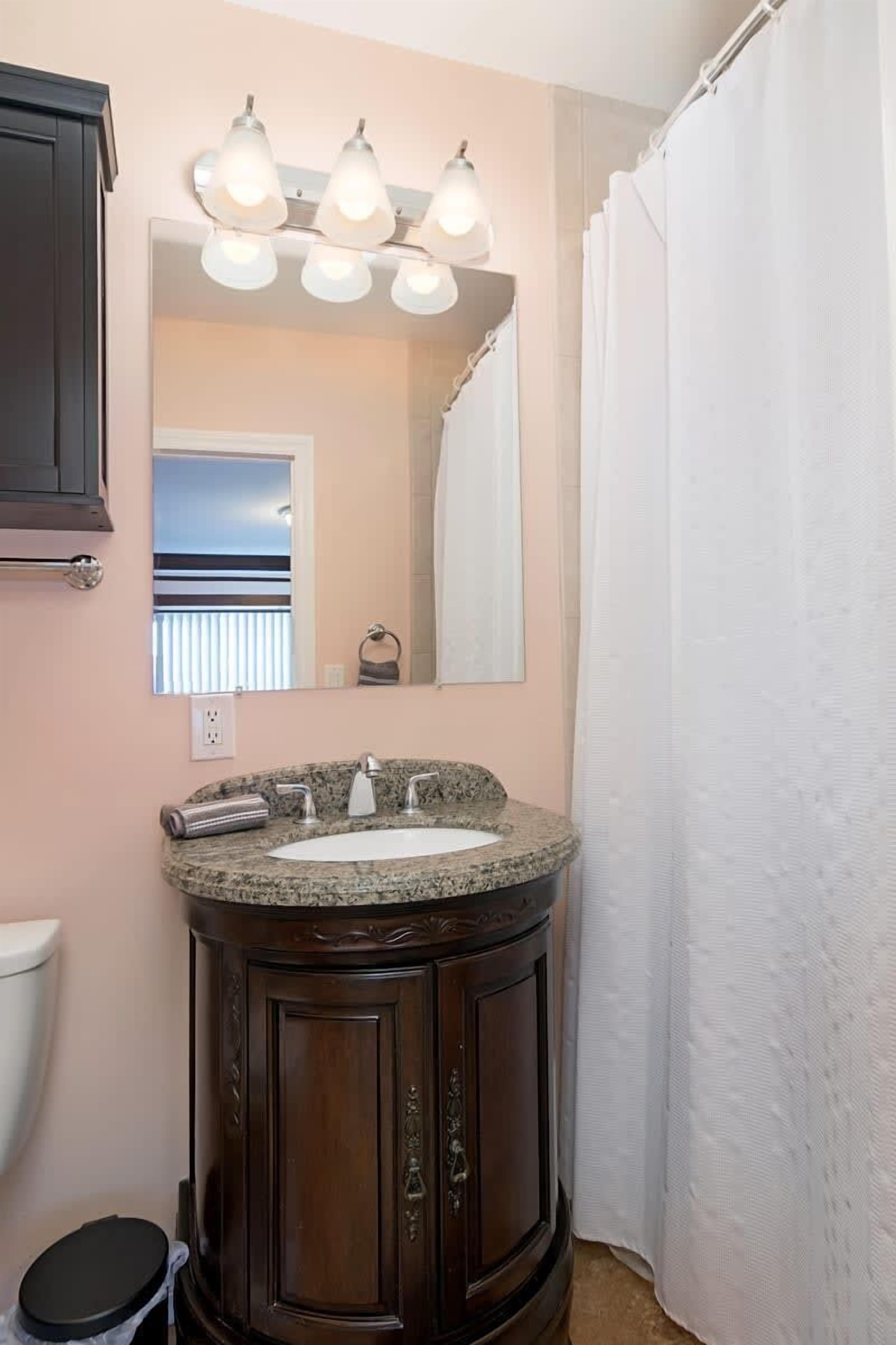 Une salle de bain équipée d’un meuble-lavabo, d’un évier, d’un miroir et d’un rideau de douche.