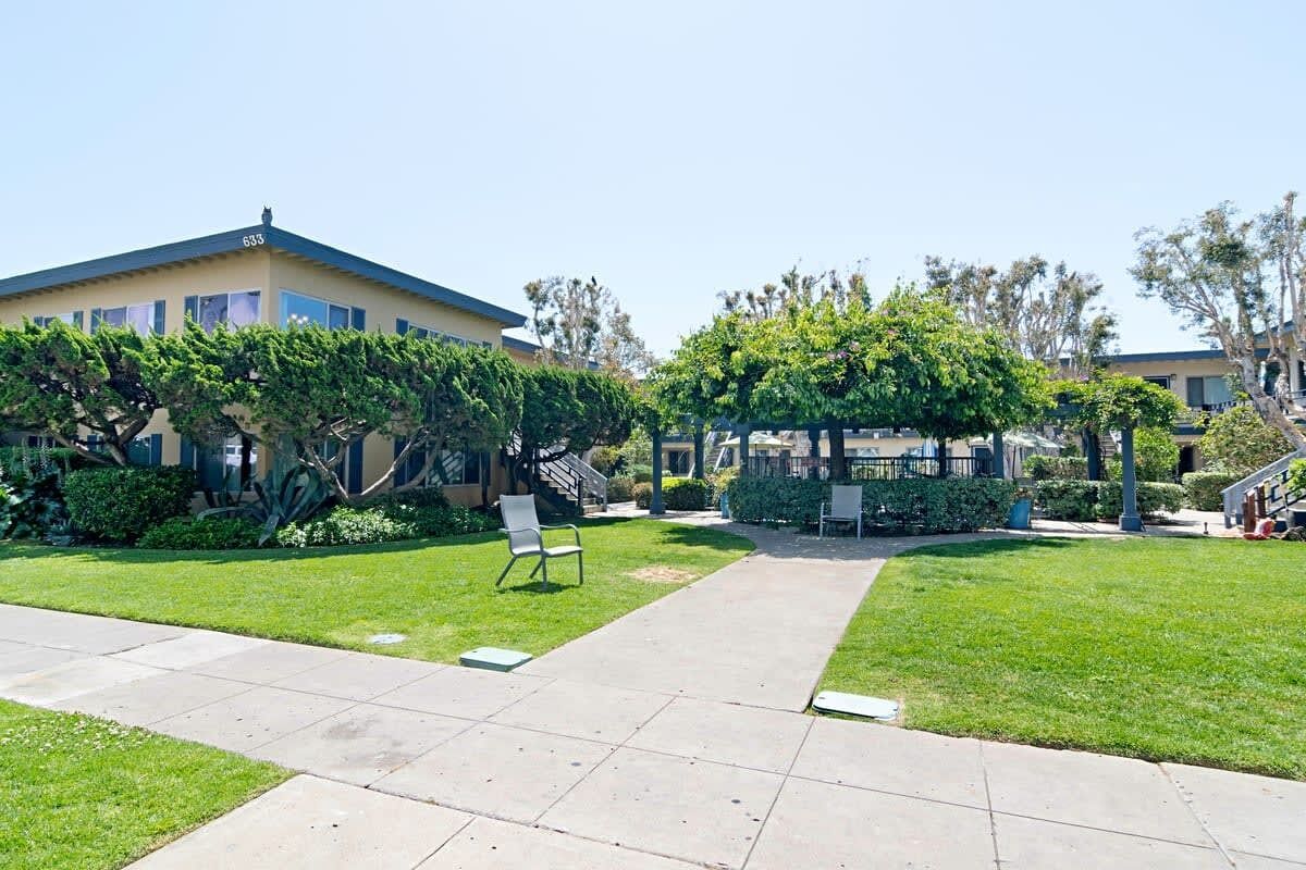 A courtyard with a building, a covered seating area, and a pathway.
