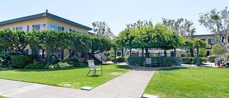 A courtyard with a building, a covered seating area, and a pathway.