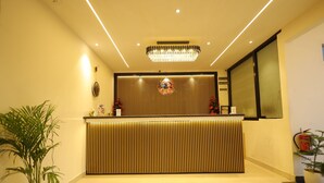 A reception area with a modern design, featuring a reception desk, a chandelier, and a potted plant. - Hotel East Gate By Vablis Hospitality (Agra)