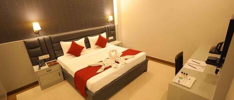 Una habitación de hotel con cama, mesitas de noche, escritorio y espejo.