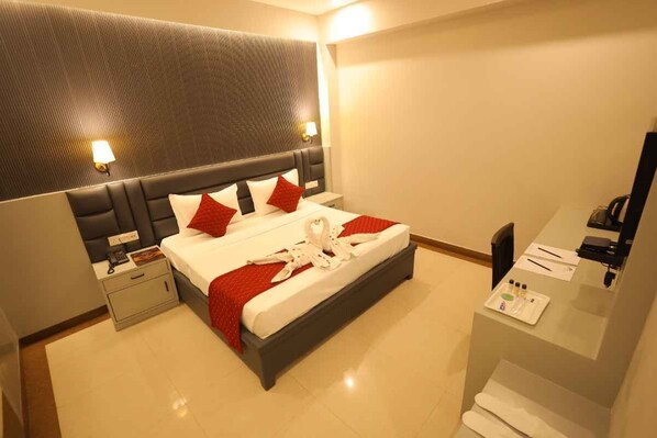 Une chambre d’hôtel avec un lit, des tables de chevet, un bureau et un miroir.