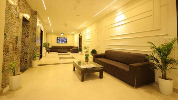 A modern hotel lobby with a sofa, coffee table, and potted plants. - Hotel East Gate By Vablis Hospitality (Agra)