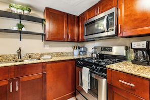 A kitchen with wooden cabinets, a stainless steel stove, a microwave, and granite countertops.