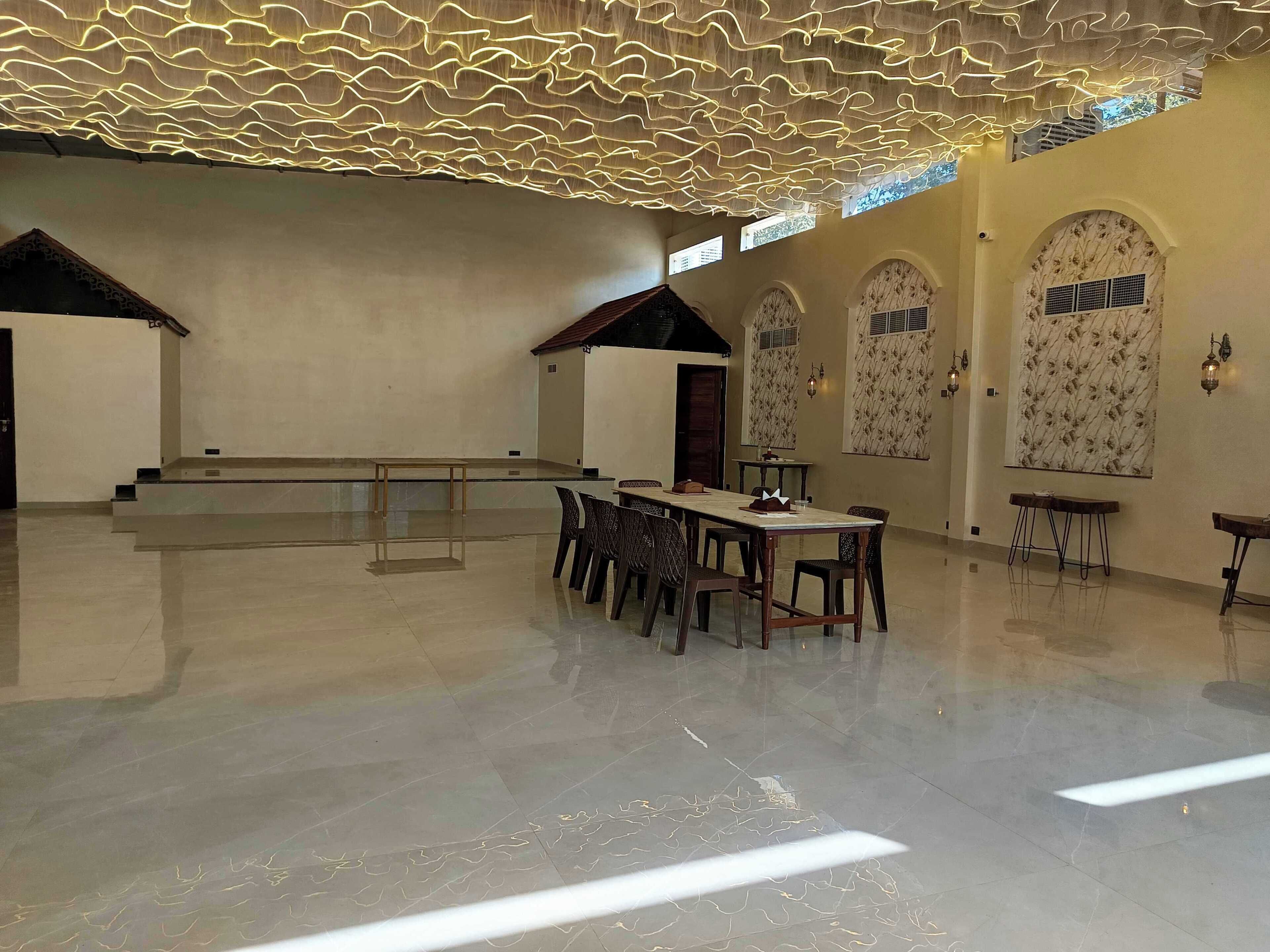 A spacious hall with a high ceiling, a long table with chairs, and arched doorways.