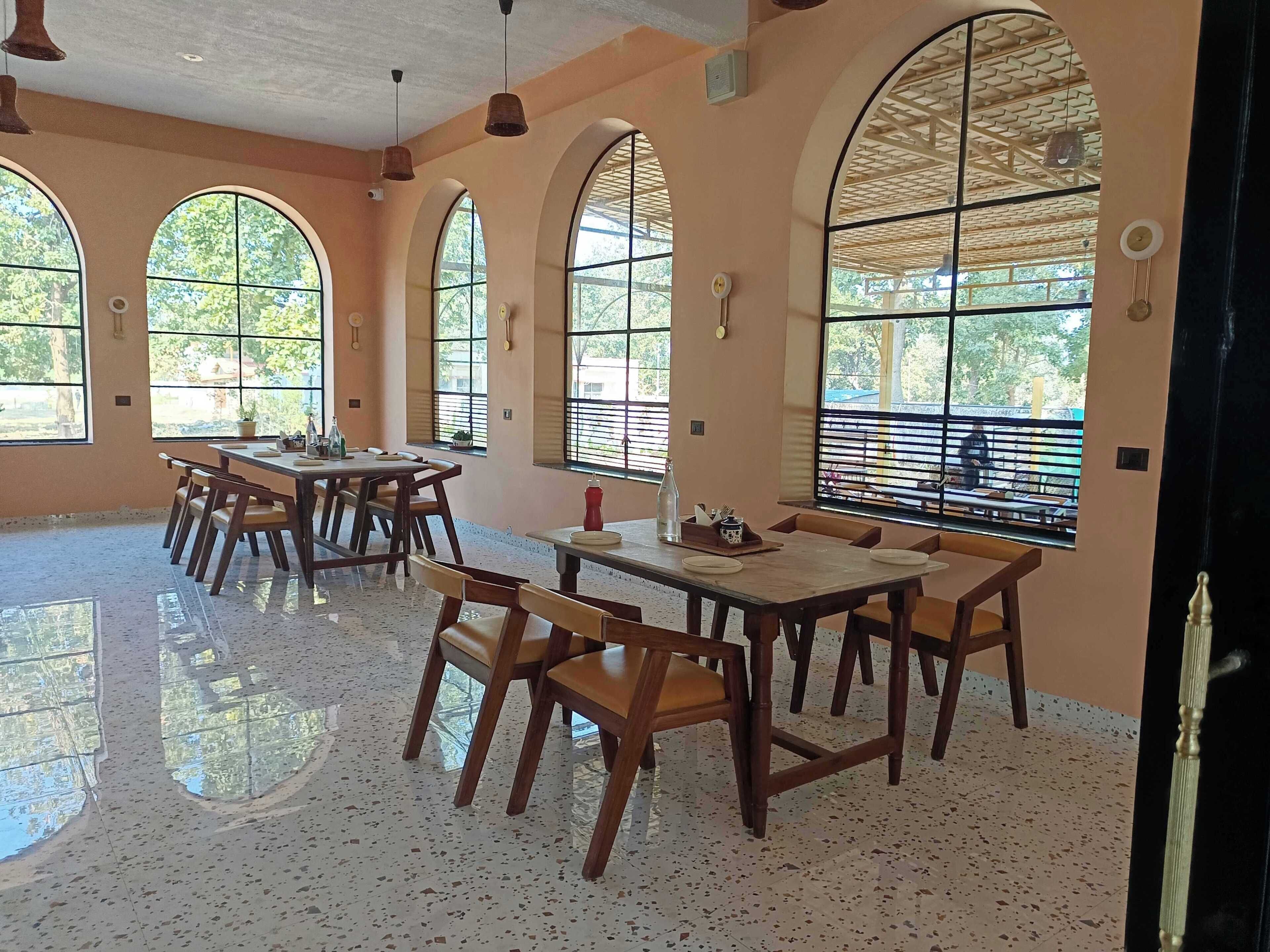 A spacious dining area with high arched windows, wooden tables, and chairs.