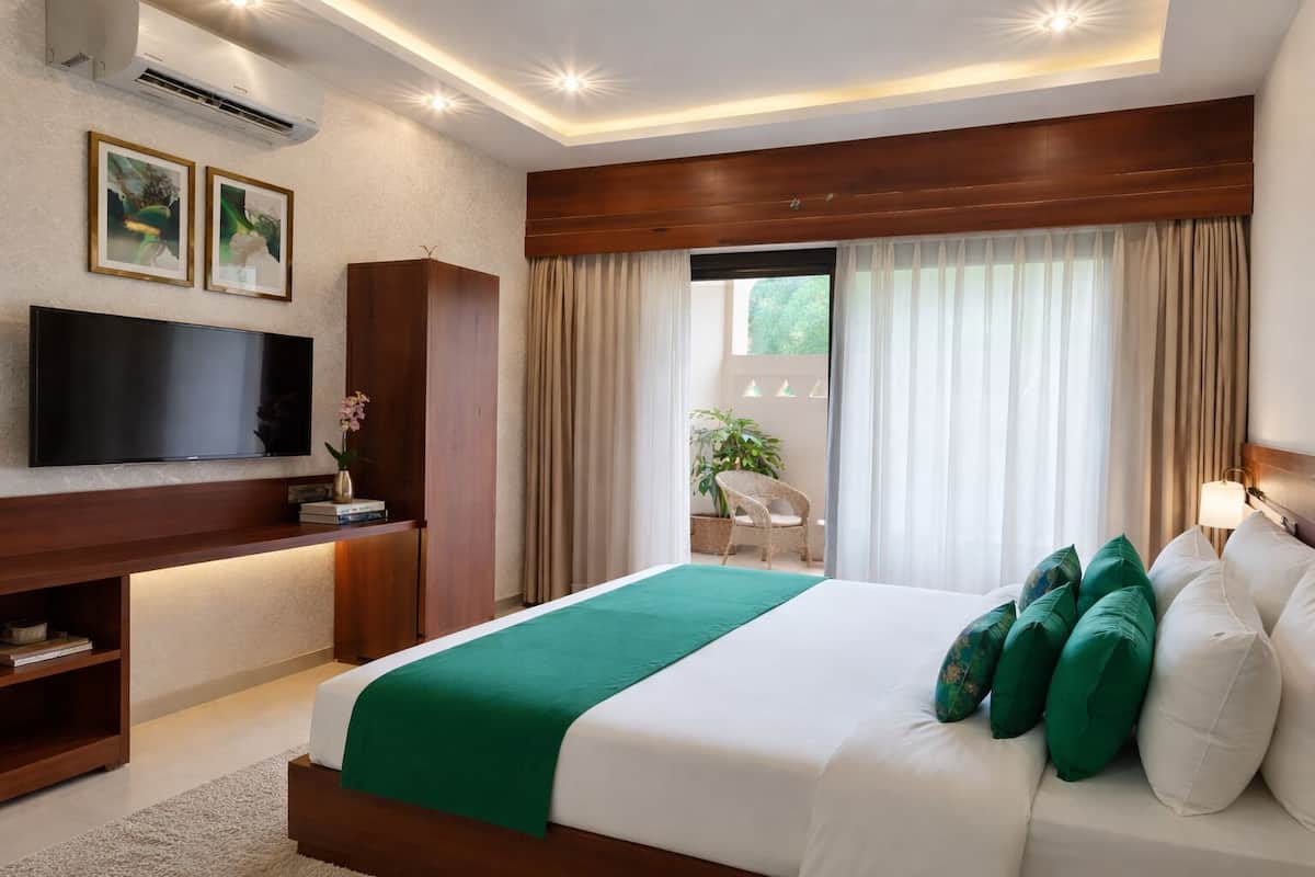 Une chambre d’hôtel moderne avec un grand lit, une télévision, une armoire en bois et un balcon avec des rideaux.