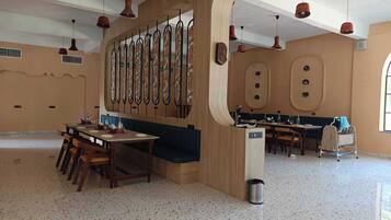 A spacious dining area with a long wooden table and chairs, a decorative wall with vertical elements, and a large window providing natural light.